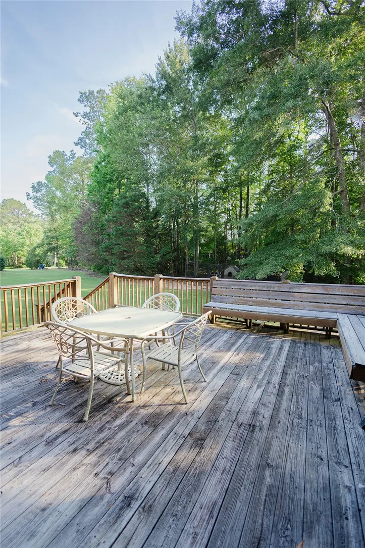 A spacious wooden deck provides ample outdoor living space, nestled among mature trees.
