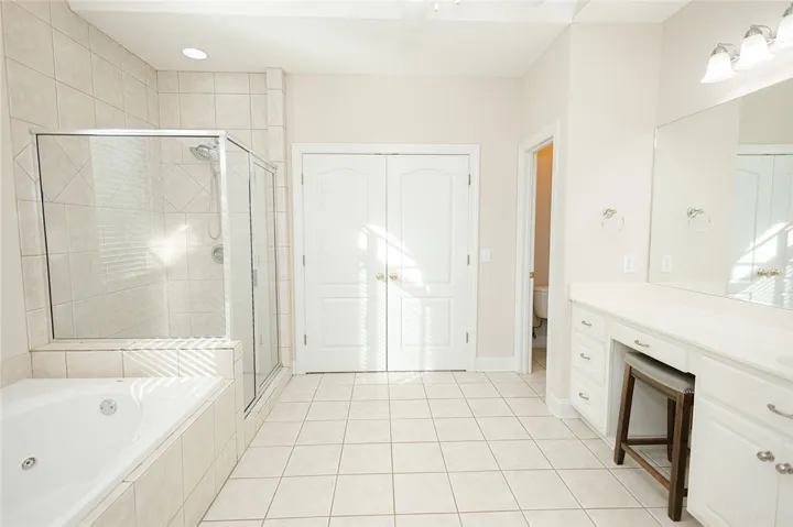 Relax and unwind in this spacious bathroom featuring a deep soaking tub and an elegant tiled shower.