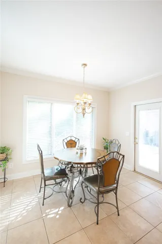 Sun-filled dining area featuring elegant tile flooring and a classic chandelier.