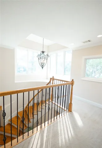 Natural light floods this inviting entryway with elegant wood and iron staircase.