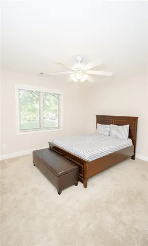 Well-lit sleeping quarters with plush carpeting and ample natural light through a generous window.