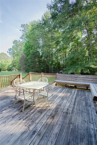 A spacious wooden deck provides ample outdoor living space, nestled among mature trees.