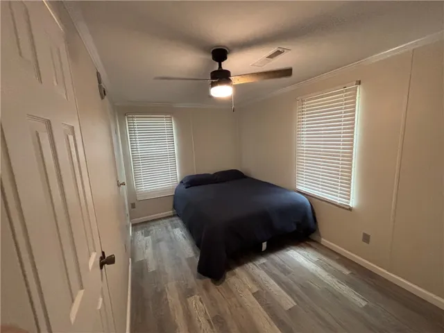 Comfortable bedroom with warm flooring and ample natural illumination for restful nights.