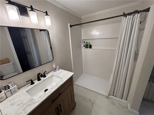 A well-appointed bath features a sleek vanity and a tiled shower with integrated shelving.
