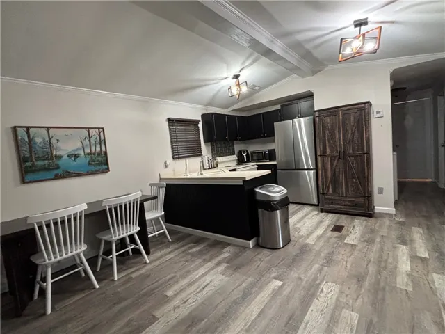 An inviting eat-in kitchen with a vaulted ceiling and a sleek stainless steel refrigerator.