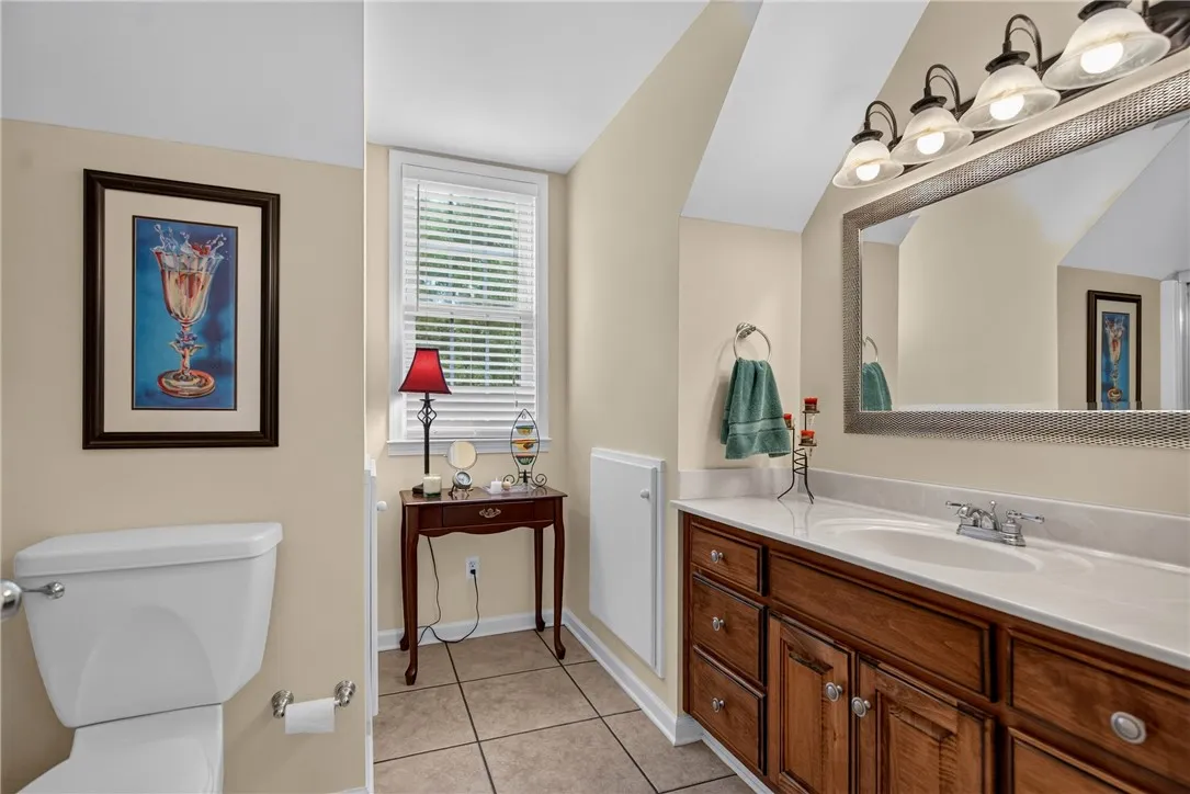 Step into a well-lit lavatory featuring a spacious vanity and neutral-toned ceramic tile flooring.