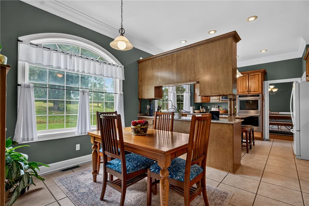 A spacious eat-in kitchen with a large arched window overlooks a scenic backyard, offering a tranquil dining experience.