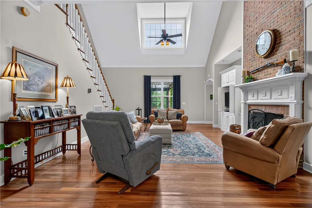 Hardwood floors flow through this inviting living room, complemented by a stately brick fireplace and a sun-filled skylight.