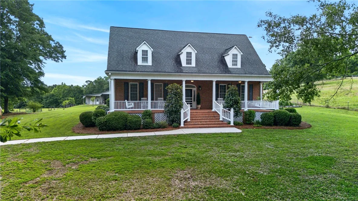 A classic brick-front home with a welcoming covered porch and pristine landscaping awaits.