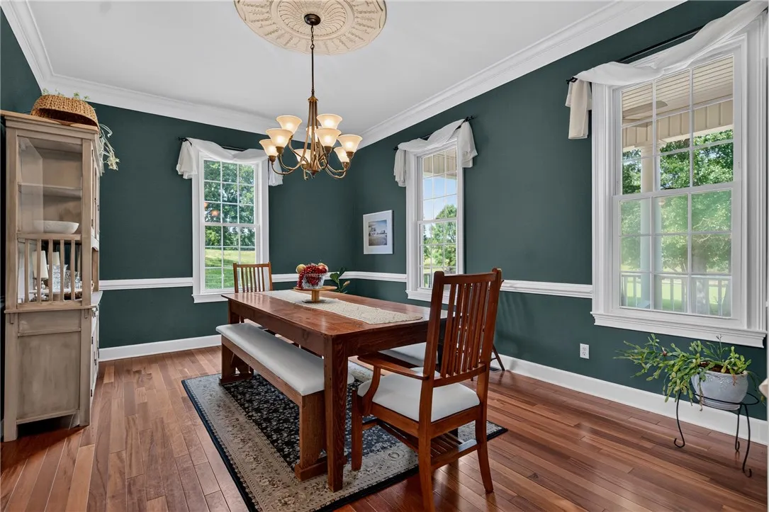 Hardwood flooring extends throughout this dining area, complemented by crisp crown molding and an elegant chandelier.
