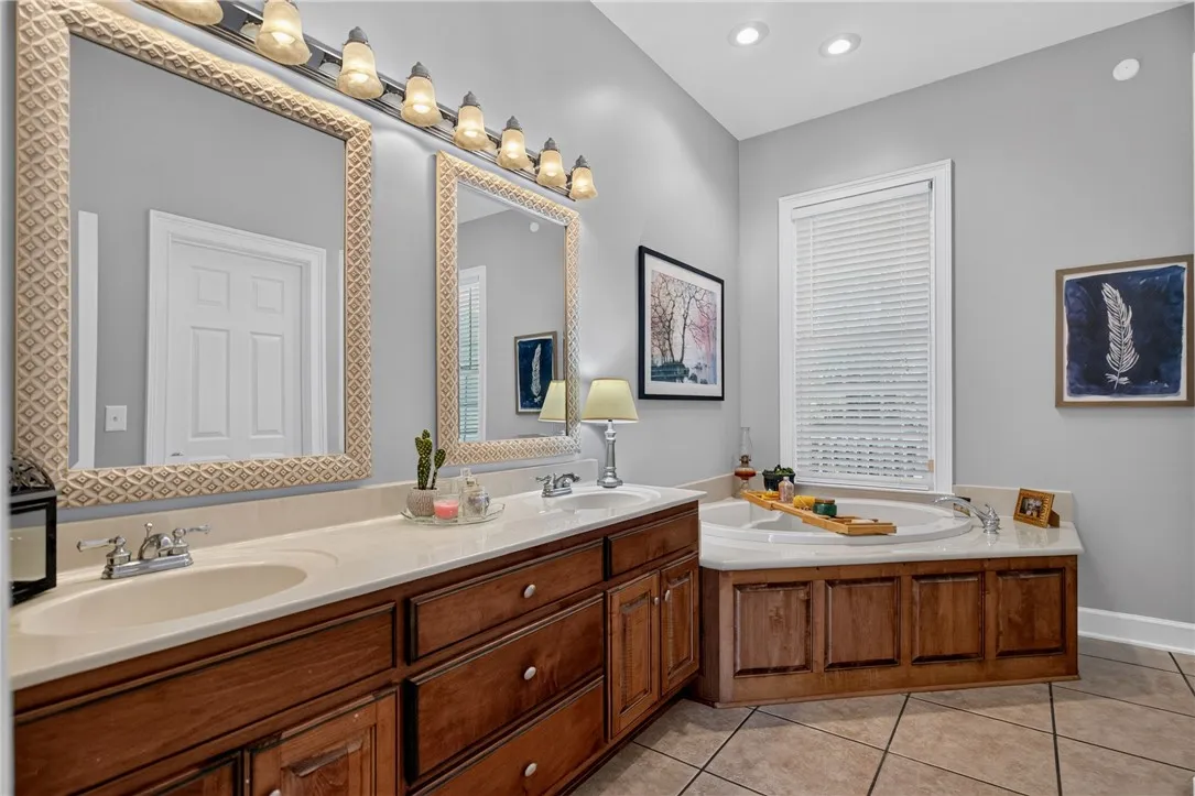 Luxurious primary bathroom featuring a spacious double vanity, a deep soaking tub, and elegant tile flooring.