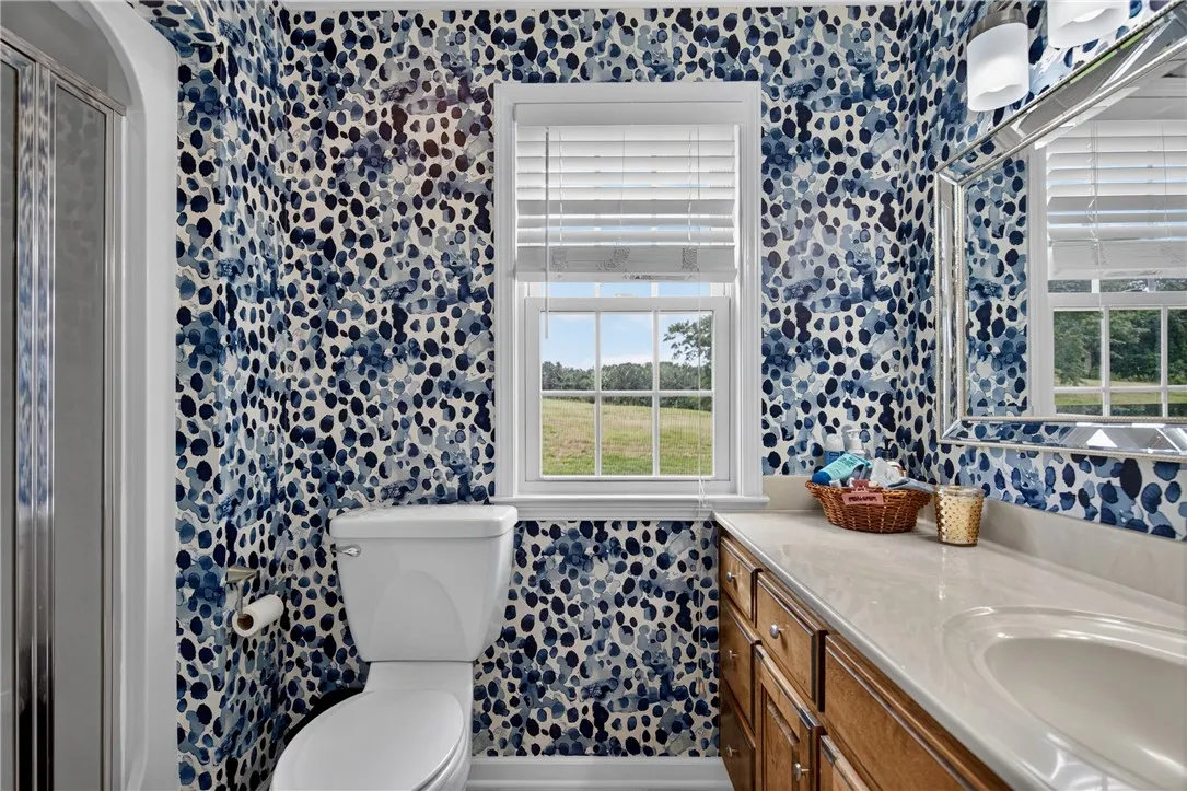 Well-lit bathroom features a spacious vanity and a serene rural outlook from the window.