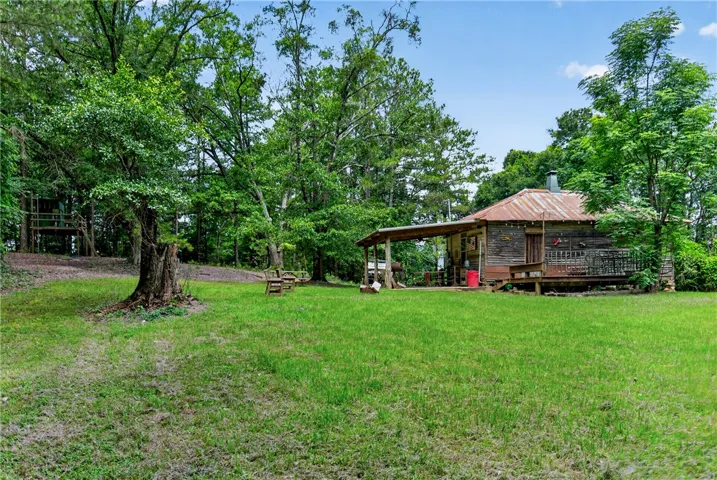 A secluded cabin, nestled amongst verdant trees, boasts a weathered porch and metal roof, offering a rustic escape.