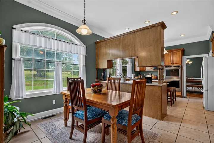 A spacious eat-in kitchen with a large arched window overlooks a scenic backyard, offering a tranquil dining experience.