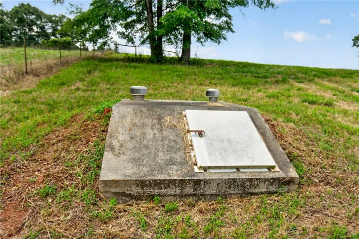 A sturdy, concrete storm shelter offers secure outdoor storage on a grassy expanse.