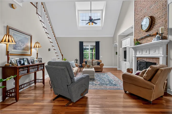 Hardwood floors flow through this inviting living room, complemented by a stately brick fireplace and a sun-filled skylight.