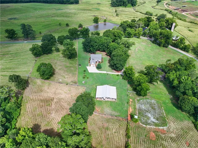 Discover vast green acreage with a private pond and multiple structures on this expansive property.