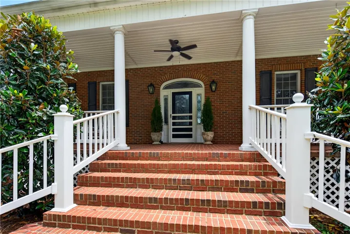A classic brick facade welcomes guests with a spacious covered porch and inviting entry steps.