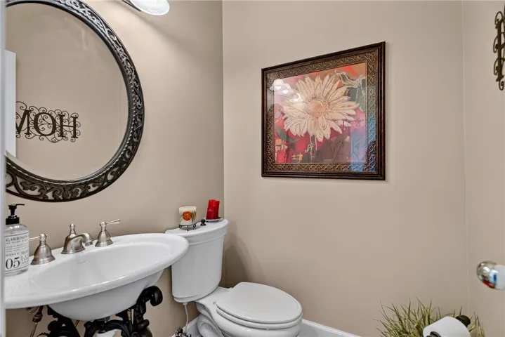 A well-appointed lavatory features an elegant pedestal sink, and decorative wall art.