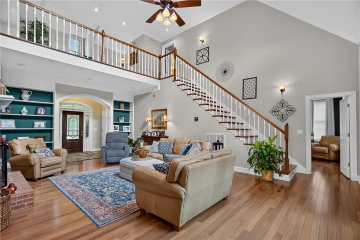 An inviting interior with soaring ceilings, a grand staircase, and a charming upper-level balcony.