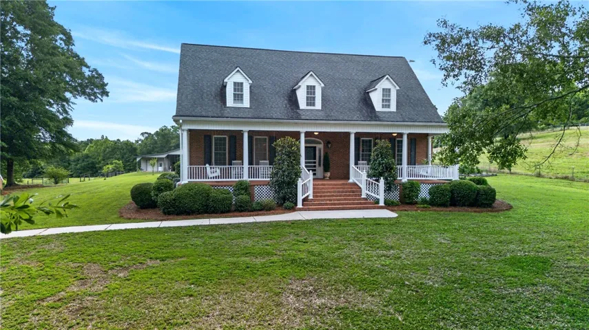 A classic brick-front home with a welcoming covered porch and pristine landscaping awaits.