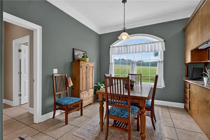 Natural light illuminates this cozy dining area, featuring practical tiled flooring and an unobstructed verdant landscape view.