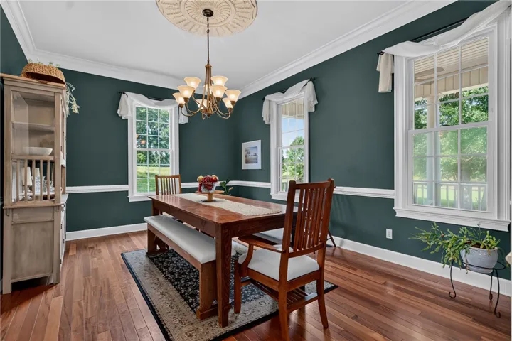 Hardwood flooring extends throughout this dining area, complemented by crisp crown molding and an elegant chandelier.