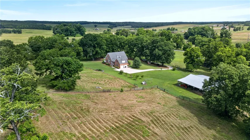 Vast green acreage surrounds a traditional brick residence and an ample outbuilding, offering serene country living.