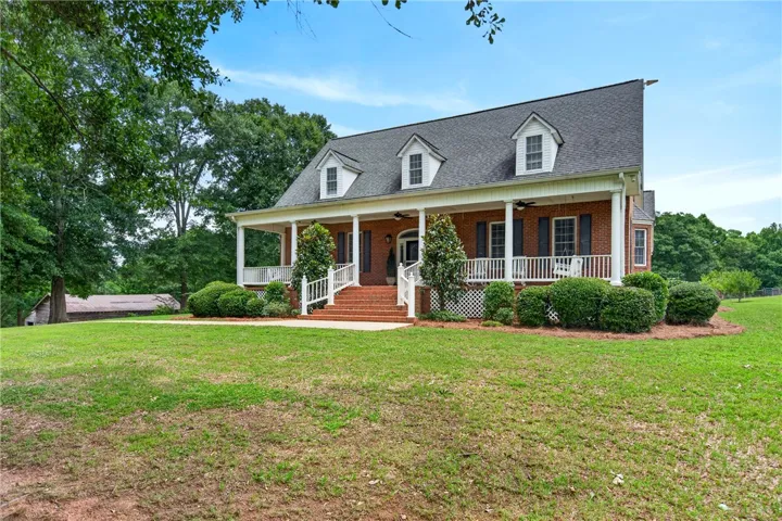 Brick facade with welcoming front porch and mature landscaping create inviting curb appeal.