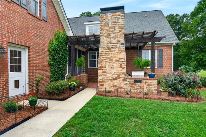 A classic brick exterior with a stone chimney and charming pergola, perfect for outdoor living.