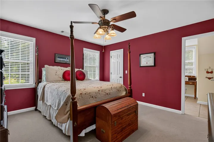 Carpeted bedroom with natural light and a classic wooden bed frame for comfortable living.