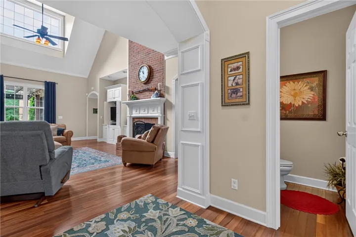 A comfortable family room with vaulted ceilings, a brick fireplace, and gleaming hardwood floors.