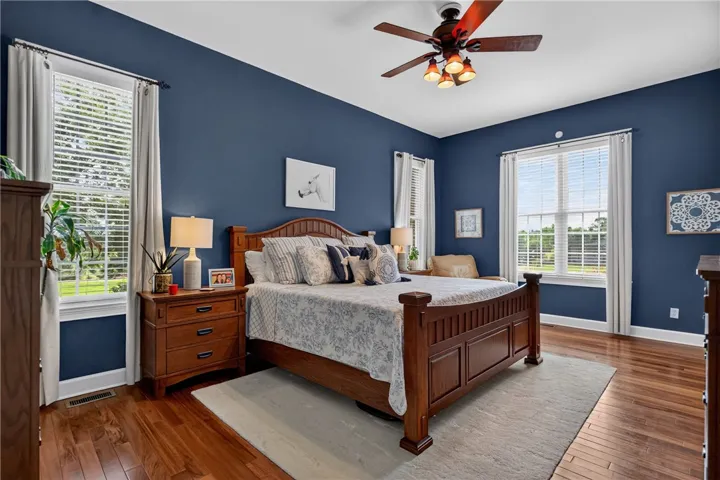 Hardwood floors and generous windows adorn this peaceful primary bedroom, creating a comfortable retreat.
