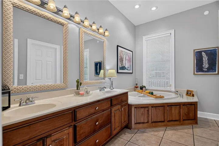 Luxurious primary bathroom featuring a spacious double vanity, a deep soaking tub, and elegant tile flooring.