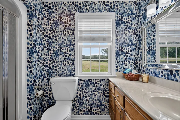 Well-lit bathroom features a spacious vanity and a serene rural outlook from the window.