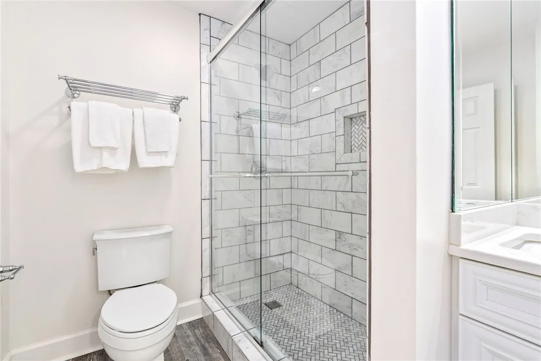 White subway tiles adorn the sleek glass shower enclosure and the crisp vanity in this immaculate bathroom.
