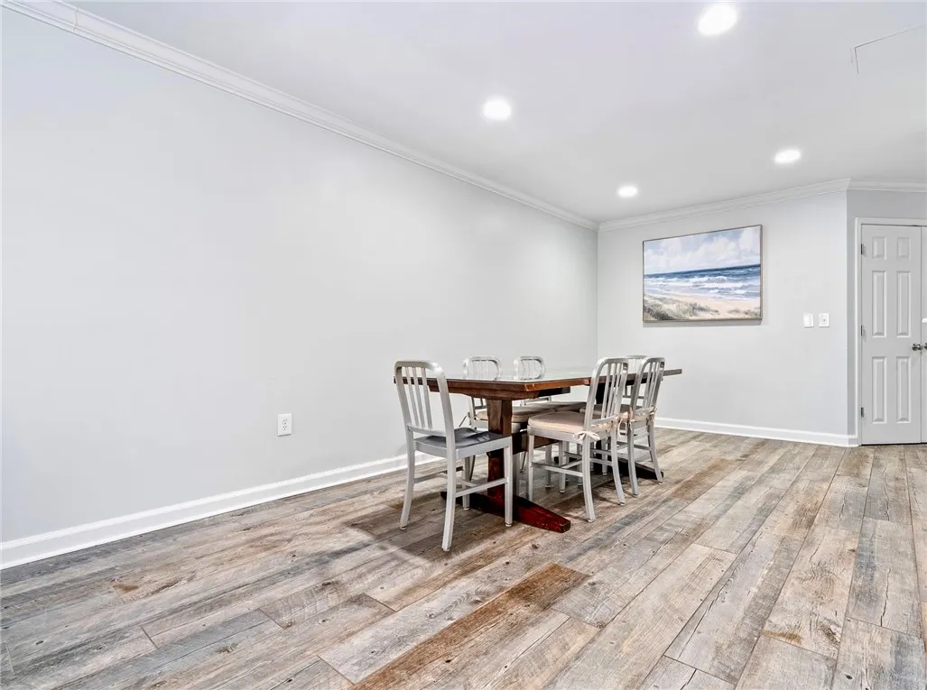 Recessed lighting illuminates this versatile space, featuring durable wood flooring and elegant crown molding.