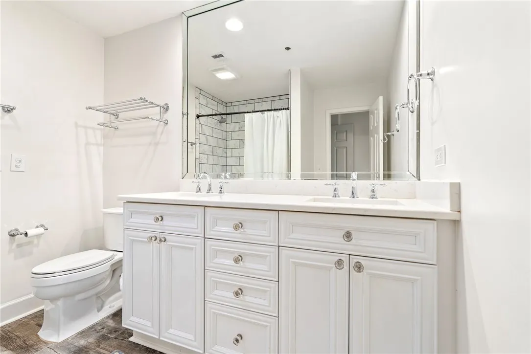 A well-lit primary bathroom featuring a double vanity with white cabinetry and a spacious mirror.