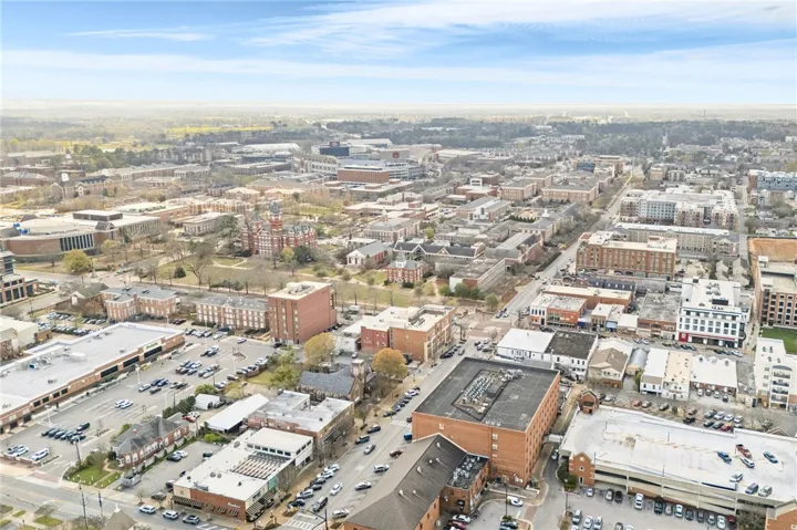 A dynamic aerial view showcases the vibrant cityscape with diverse buildings and abundant parking facilities.