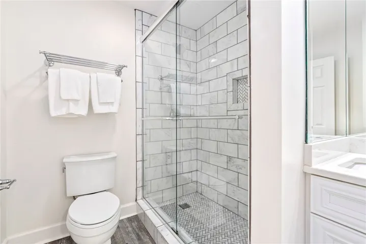 White subway tiles adorn the sleek glass shower enclosure and the crisp vanity in this immaculate bathroom.
