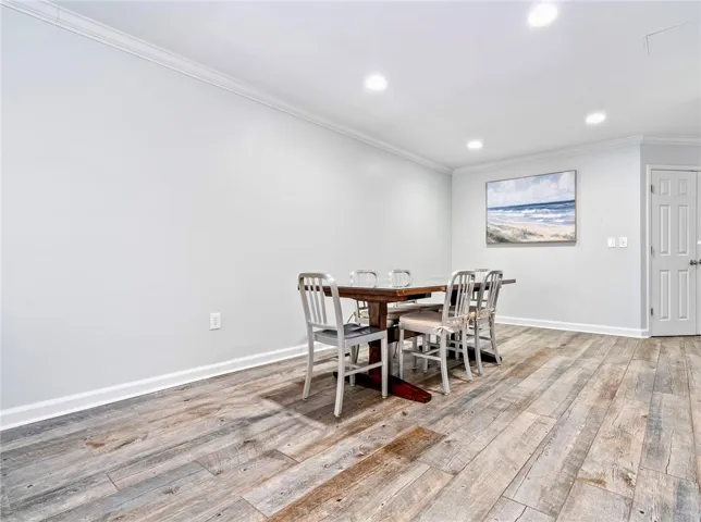 Recessed lighting illuminates this versatile space, featuring durable wood flooring and elegant crown molding.