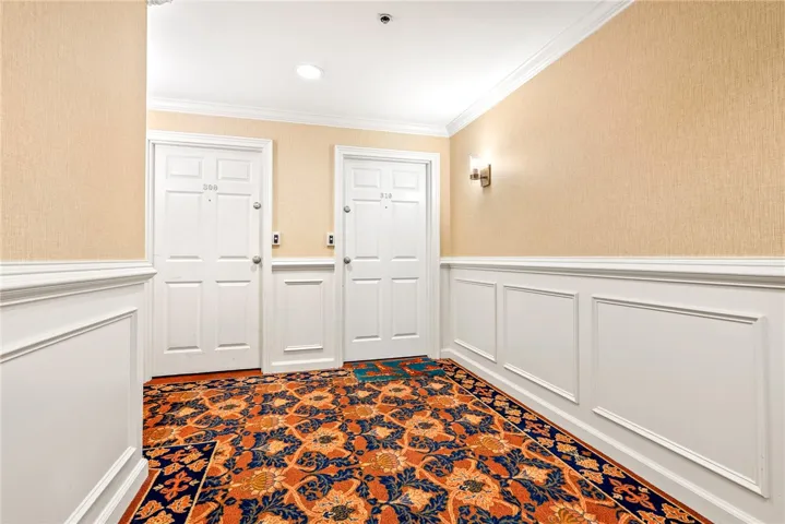 A welcoming entryway with classic wainscoting and a richly patterned carpet.