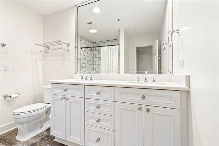 A well-lit primary bathroom featuring a double vanity with white cabinetry and a spacious mirror.