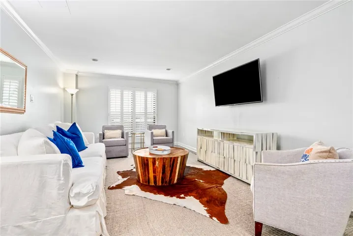 Crisp white walls and crown molding define this well-lit living area, perfect for relaxation.