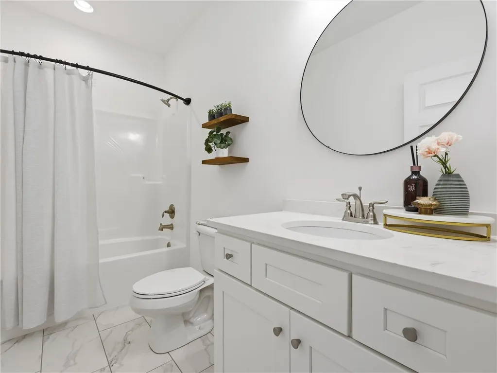 Marble-look flooring and a clean vanity define this bright and inviting full bathroom.