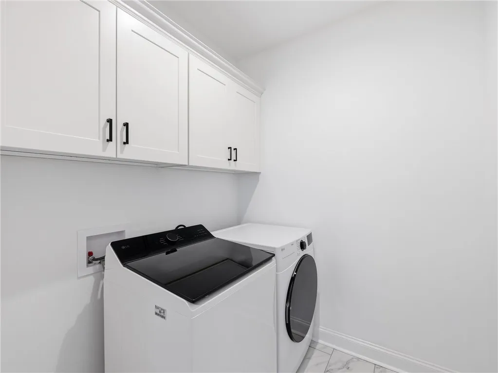 Ample cabinetry and modern appliances define this pristine laundry space.
