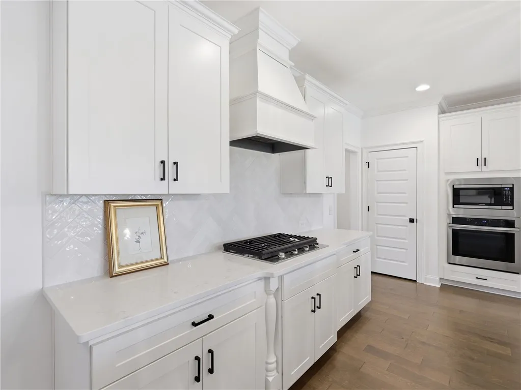 White cabinetry, solid surface counters, and modern appliances outfit this sleek kitchen.