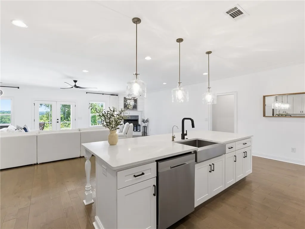 A well-appointed kitchen island with gleaming countertops and elegant pendant lights seamlessly transitions into a comfortable living space with a picturesque outdoor view.