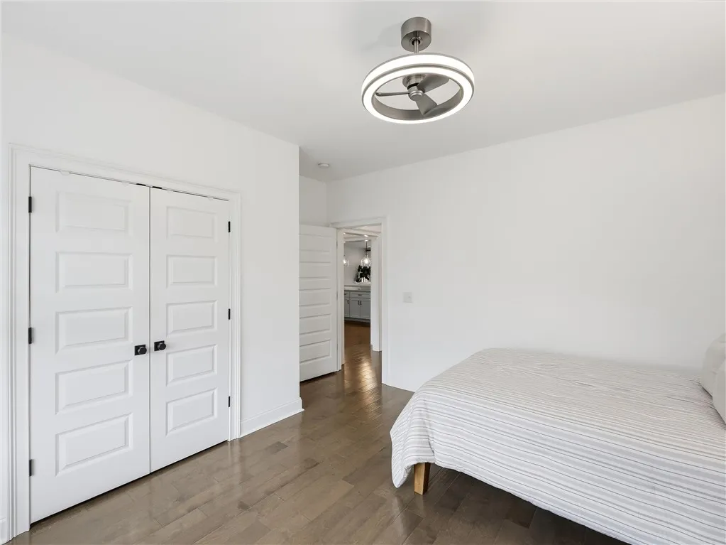 Hardwood floors and a bright overhead light fixture define this welcoming bedroom.