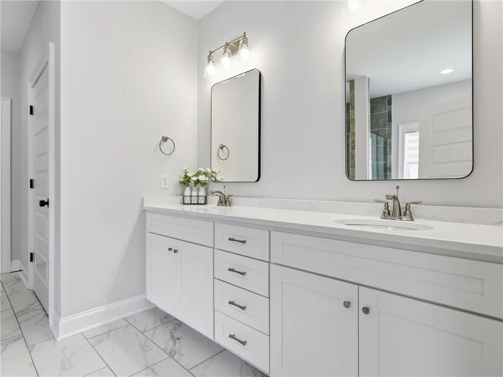 Dual vanities and sleek mirrors adorn this pristine primary bathroom, offering ample space and contemporary design.